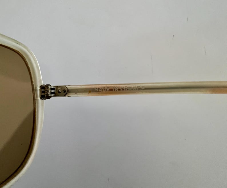 K&ouml;nnte beinhalten: Eine wei&szlig;e Keramik-Tasse mit schwarzem Henkel und dem Text "But First, Coffee" in fetter, schwarzer Schrift. Die Tasse steht vor einem verschwommenen Hintergrund, der eine gem&uuml;tliche Umgebung suggeriert. Die Tasse ist etwa 10 cm hoch.