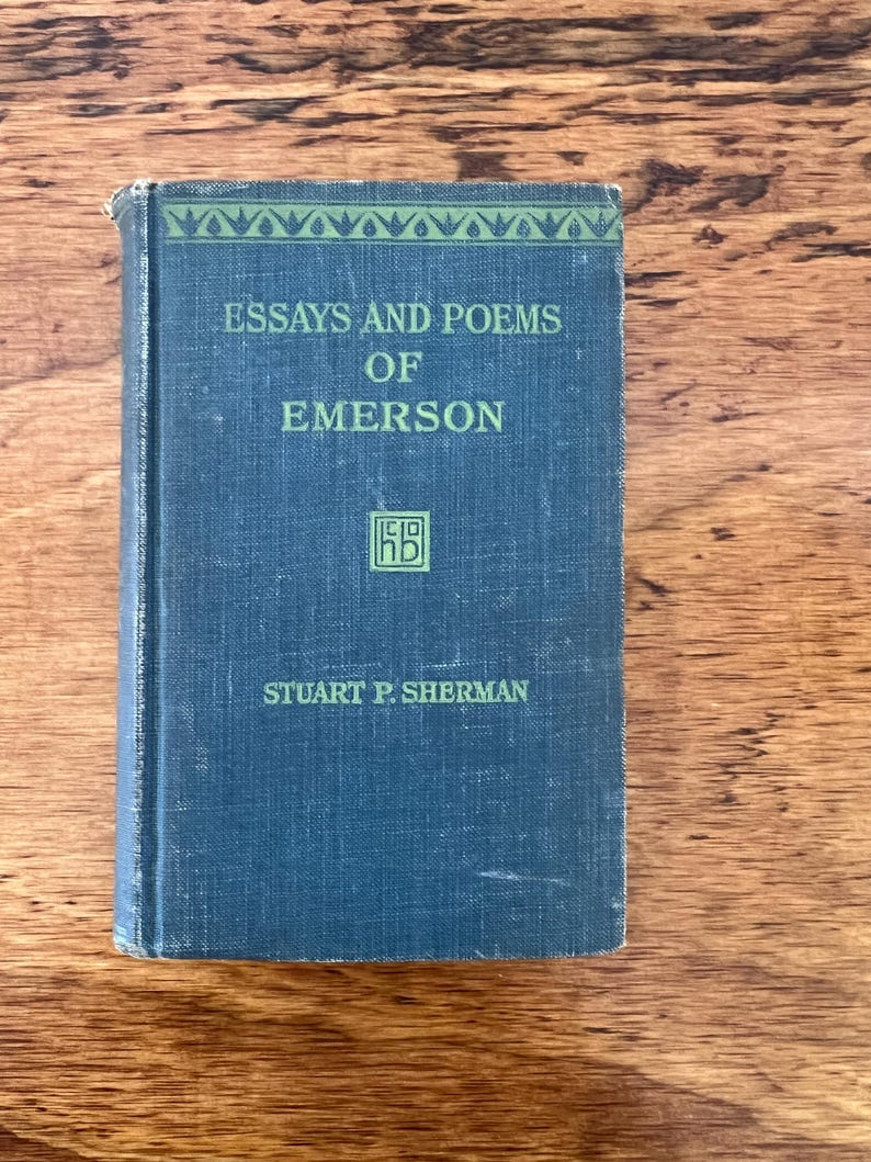 May include: A blue book with the title "Essays and Poems of Emerson" by Stuart P. Sherman. The book has a green border around the title and a small green square with the letters "HB" in the center.