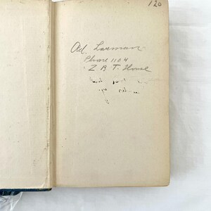 May include: A close-up of the inside cover of a book with handwritten text. The text reads "Ad. Laussman, Phone 1104, Z.B.T. House". The number "120" is written in the top right corner of the page.