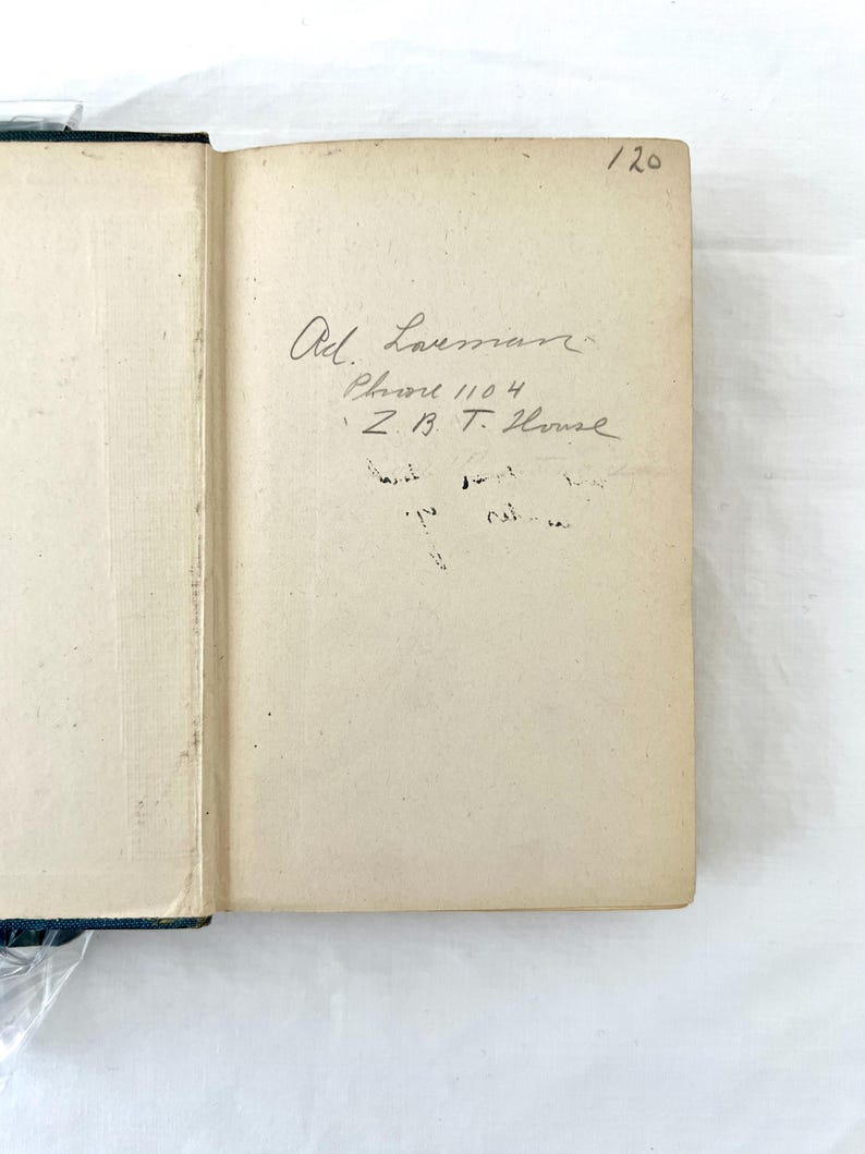 May include: A close-up of the inside cover of a book with handwritten text. The text reads "Ad. Laussman, Phone 1104, Z.B.T. House". The number "120" is written in the top right corner of the page.
