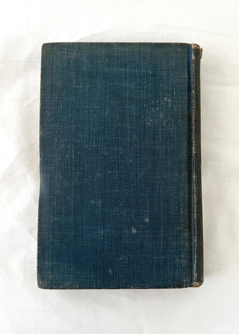 May include: A dark blue hardcover book with a textured fabric cover. The book has a spine with gold lettering.