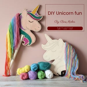 Op de afbeelding: DIY eenhoorn knutselset met twee houten eenhoofd uitsparingen, een geschilderd en een ongeschilderd, met regenboog garen manen en kleurrijke garen ballen. De tekst "DIY Unicorn fun" en "By BasMakes" zijn ook zichtbaar.