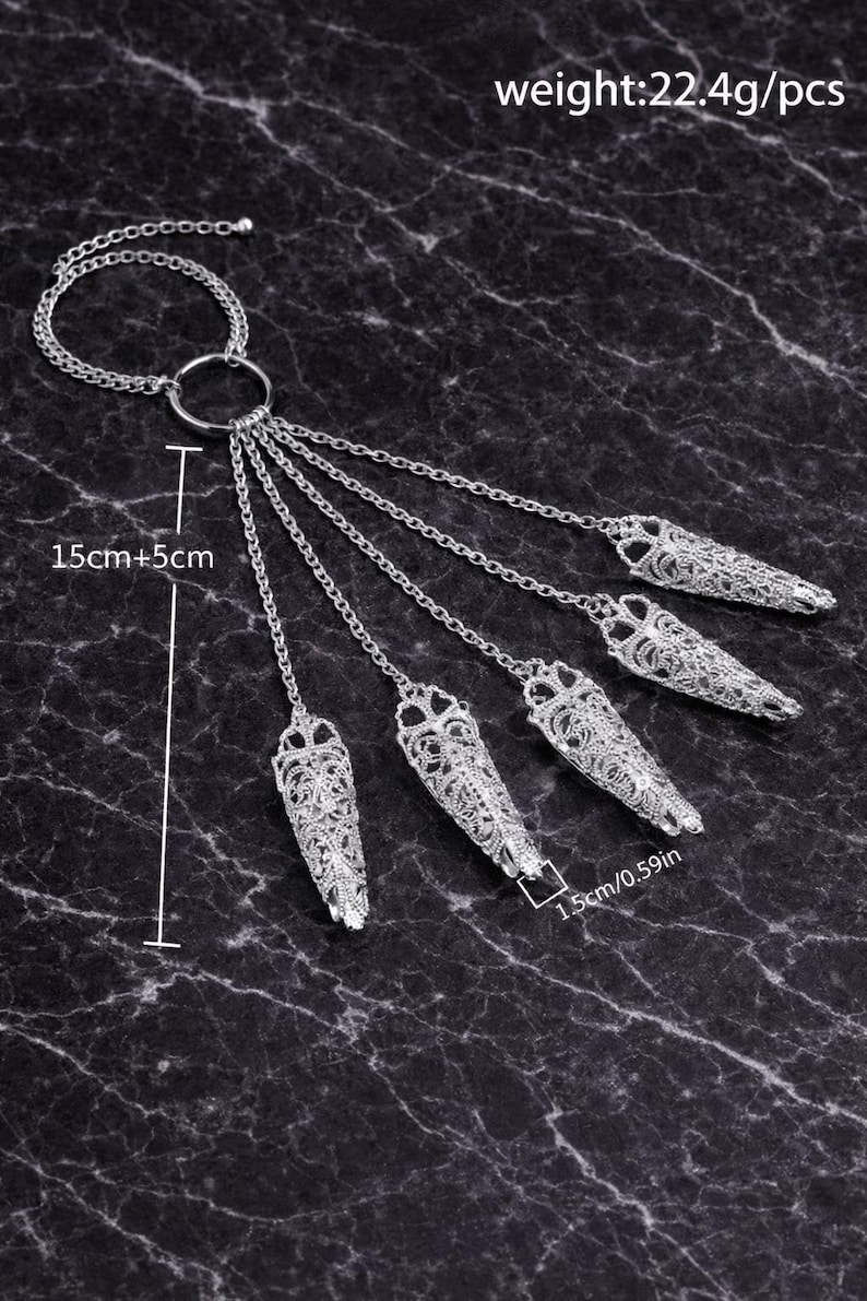 May include: Silver-toned finger armor jewelry with intricate filigree design. The set includes a ring connected to five finger covers by chains. Each finger cover is 1.5cm (0.59in) long. The total length is 20cm (7.87in).