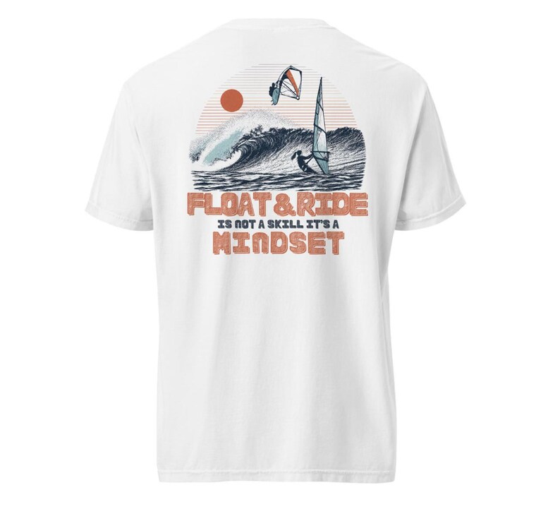 May include: White t-shirt with a graphic on the back featuring a windsurfer on a wave, a setting sun, and the text "FLOAT & RIDE IS NOT A SKILL IT'S A MINDSET" in orange and brown. The design evokes a beach and water sports theme.