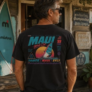 May include: Black t-shirt with a colorful graphic featuring "Maui World Cup '89" text and a windsurfer design. The shirt has a vintage look and feel, perfect for fans of watersports and surfing.