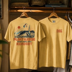 May include: Mustard yellow t-shirts with a graphic design. One shirt features a wave, a person windsurfing, and the text "FLOAT & RIDE IS NOT A SKILL IT'S A MINDSET." The other shirt has the text "FLOAT & RIDE."