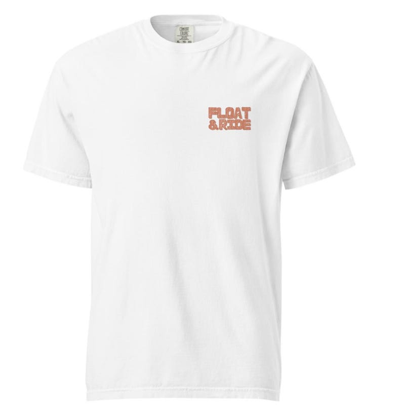 May include: A white short-sleeved t-shirt with the text "FLOAT & RIDE" in a coral-colored, blocky font on the upper left chest. The shirt has a crew neck and a relaxed fit.