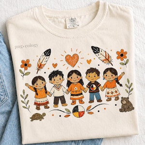 Op de afbeelding: Een crèmekleurig t-shirt met een grafische illustratie van vijf kinderen die elkaars hand vasthouden. Het ontwerp bevat oranje bloemen, veren, een hart, een schildpad, een beer en een medicijnwiel. De tekst "png.ecology" staat aan de linkerkant.