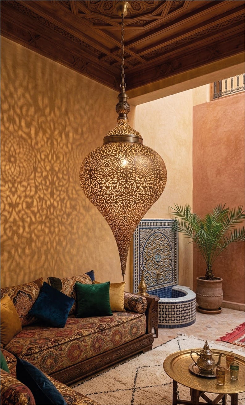Op de afbeelding: Een grote, druppelvormige hanglamp van geperforeerd messing met ingewikkelde, herhalende geometrische patronen. Het metalen oppervlak heeft een warme afwerking die gedetailleerde, sierlijke schaduwen op de omliggende muren werpt.
