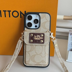 以下が含まれることがあります： ベージュとタンのモノグラム柄のスマートフォンケース。黒い縁取りと取り外し可能なクロスボディストラップが付いています。ケースの背面にはダークブラウンの長方形のポケットがあり、金色の馬と馬車のロゴと4つのリベットがあしらわれています。