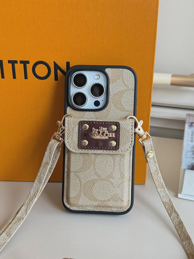 以下が含まれることがあります： ベージュとタンのモノグラム柄のスマートフォンケース。黒い縁取りと取り外し可能なクロスボディストラップが付いています。ケースの背面にはダークブラウンの長方形のポケットがあり、金色の馬と馬車のロゴと4つのリベットがあしらわれています。