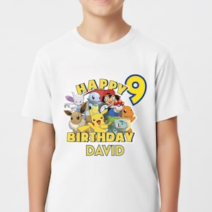 May include: White t-shirt featuring a colorful graphic of various cartoon characters, the number 9, and the text "HAPPY BIRTHDAY DAVID" in yellow and blue. The shirt is made of a soft material.