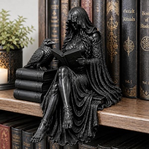May include: A black resin figurine of a hooded figure sitting on a stack of books while reading, accompanied by a raven perched on the books. The figure wears a long, flowing gown with intricate textures and is barefoot, with detailed musculature.