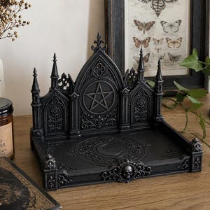 Peut inclure: Plateau d'autel gothique noir avec pentagramme, roses et crâne. Le plateau présente un dos surélevé avec des flèches et un motif de croissant de lune. Décoration pour un intérieur gothique.