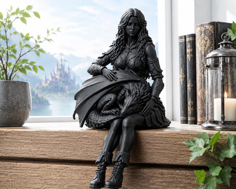 May include: A matte black figurine depicting a long-haired figure in armor and boots sitting while cradling a dragon with folded wings. The sculpture features intricate textures on the dragon scales and the figure's attire, rendered in a solid dark tone.
