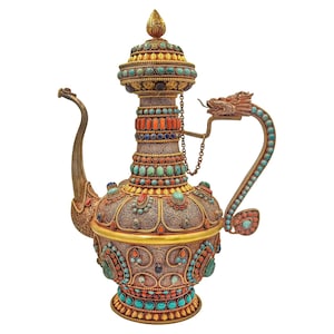 Puede incluir: Tetera plateada ornamentada con detalles turquesa, coral y lapislázuli. La tetera presenta un asa y un pico en forma de dragón, y está adornada con intrincados filigranas y elementos decorativos. La tapa está rematada con un remate dorado.