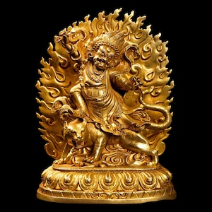 May include: A golden statue of a deity riding a tiger, surrounded by flames. The figure has a fierce expression and is adorned with intricate details. The statue is set against a black background.