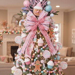 May include: A Christmas tree decorated with pastel-colored ornaments including gingerbread figures, cupcakes, donuts, and lollipops. A large pink and white striped bow sits at the top, centered below a gingerbread person wearing a pink hat.