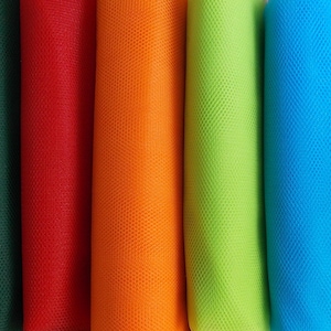 May include: A close-up of several rolls of colorful mesh fabric. The colors include black, dark green, red, orange, lime green, blue, and light blue. The fabric has a small, evenly spaced hole pattern.