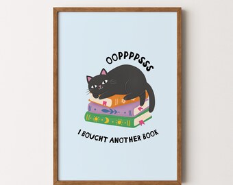 May include: A framed print featuring a black cat lounging on a stack of books. The print has the text "OOPPPSSS" above the cat and "I BOUGHT ANOTHER BOOK" below. The background is light blue.