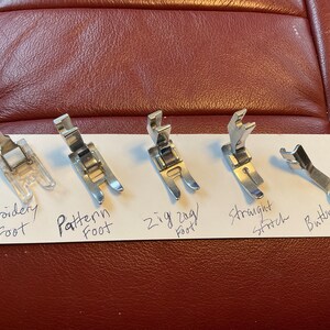 Peut inclure: Cinq pieds de machine &agrave; coudre diff&eacute;rents&nbsp;: pied pour broderie, pied pour motif, pied pour point zigzag, pied pour point droit et pied pour bouton.
