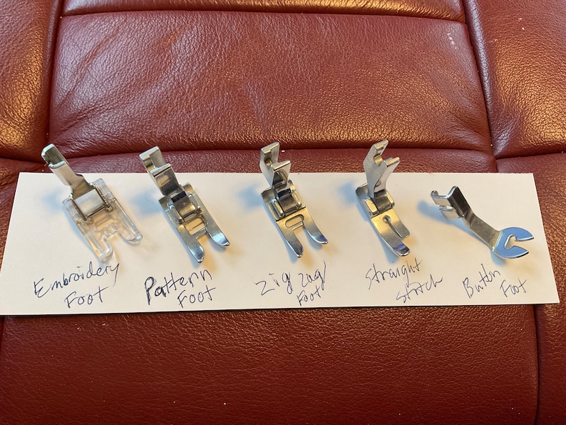 Peut inclure: Cinq pieds de machine &agrave; coudre diff&eacute;rents&nbsp;: pied pour broderie, pied pour motif, pied pour point zigzag, pied pour point droit et pied pour bouton.