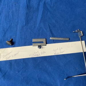 Peut inclure: Un ensemble de pi&egrave;ces de machine &agrave; coudre comprenant un pied, une vis, une plaque de pied d'entra&icirc;nement zigzag, un prolongateur d'axe de bobine et un crochet en m&eacute;tal.