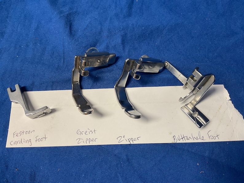 Peut inclure: Quatre pieds de machine &agrave; coudre&nbsp;: un pied de feston pour cordon argent&eacute;, un pied de fermeture &eacute;clair greist argent&eacute;, un pied de fermeture &eacute;clair argent&eacute; et un pied de boutonni&egrave;re argent&eacute;.