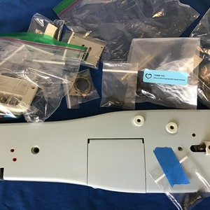 May include: A light gray sewing machine part with a small rectangular opening and four red dots. The part is surrounded by several clear plastic bags containing various small metal parts and a sticker that says "Thank You! etsy.com/shop/prettyyearhome".