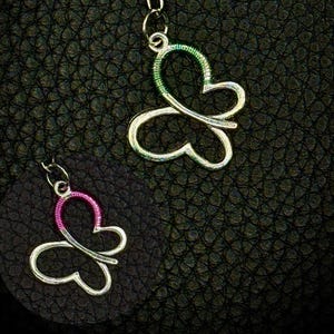 May include: Two butterfly pendants. One pendant has a silver outline with a green wire-wrapped design, and the other has a silver outline with a pink wire-wrapped design. Both pendants are attached to a silver chain.
