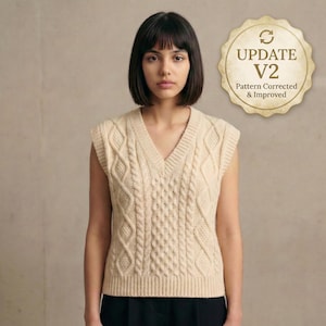 Könnte beinhalten: Eine cremefarbene Strickweste mit V-Ausschnitt. Die Weste hat ein detailliertes Muster aus geflochtenen Kabeln und Rauten. Das Bild enthält ein rundes Emblem mit dem Text "UPDATE V2 Pattern Corrected & Improved".