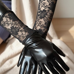 May include: A pair of black gloves with a shiny surface, complemented by black floral lace accents on the upper arm. The gloves appear to be made from a smooth material, possibly leather, and cover the hands, extending up the forearm.