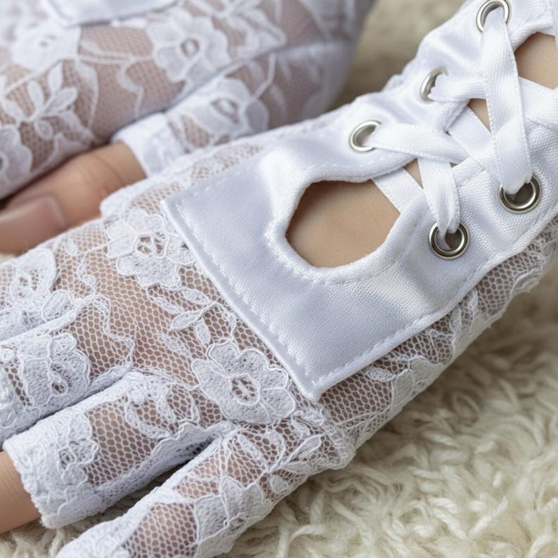 Peut inclure: Gants sans doigts en dentelle blanche avec un poignet en satin et un la&ccedil;age en ruban. Les gants pr&eacute;sentent un motif de dentelle florale d&eacute;licate et sont con&ccedil;us avec une paume ouverte. Le poignet en satin a une petite ouverture.