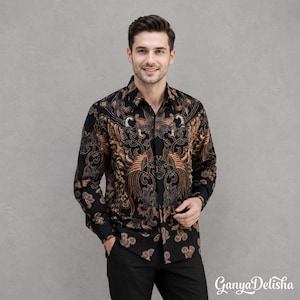 May include: A long-sleeved button-down shirt featuring a black and brown batik pattern with intricate swirling motifs and bird-like shapes. The shirt has a standard collar, a front button placket, and cuffed sleeves, worn with black trousers.