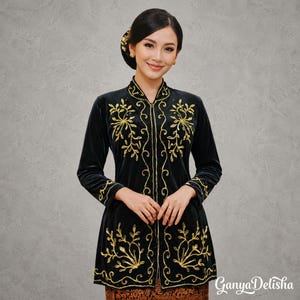 Peut inclure: Une veste noire à manches longues en velours avec des broderies dorées complexes en motifs floraux sur les panneaux avant et les poignets. Le vêtement possède un col haut, une fermeture centrale et le texte GanyaDelisha dans le coin.