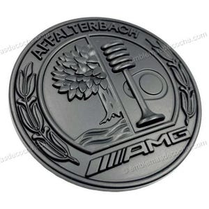 Könnte beinhalten: Ein kreisförmiges, mattschwarzes Emblem mit dem Schriftzug AFFALTERBACH oben und AMG unten. Das zentrale Design zeigt einen stilisierten Baum auf der linken Seite und ein Ventil auf der rechten Seite, eingerahmt von Lorbeerblättern am Rand.