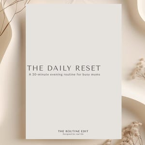Può includere: Un libro beige chiaro intitolato "THE DAILY RESET" con il sottotitolo "A 30-minute evening routine for busy mums". Il libro è su una superficie beige con piante secche decorative e il testo "THE ROUTINE EDIT" in basso.