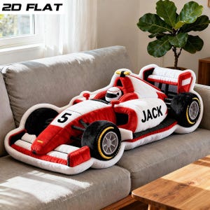 May include: A plush, red, white, and black race car pillow with the number 5 and the name "JACK" on the side. The pillow has black wheels with yellow accents and a driver figure. The text "2D FLAT" is in the upper left corner.
