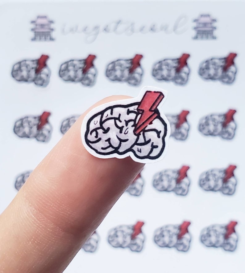 May include: A sticker featuring a cartoon brain with a red lightning bolt. The sticker is on a finger, and there are multiple copies of the sticker in the background.