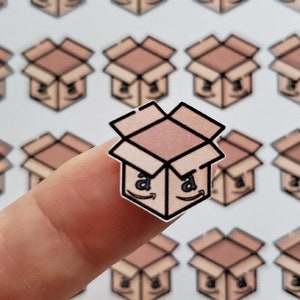 May include: A sheet of stickers featuring a repeated pattern of brown cardboard boxes with the Amazon logo. The boxes are open and have a white interior. The stickers are on a white background.