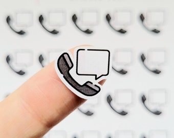 May include: A white sticker with a black outline of a phone with a speech bubble. The sticker is on a finger.