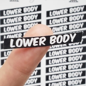 Könnte beinhalten: Ein Blatt mit schwarzen und weißen Aufklebern mit dem Text "LOWER BODY", der mehrmals wiederholt wird. Die Aufkleber sind rechteckig und haben abgerundete Ecken.