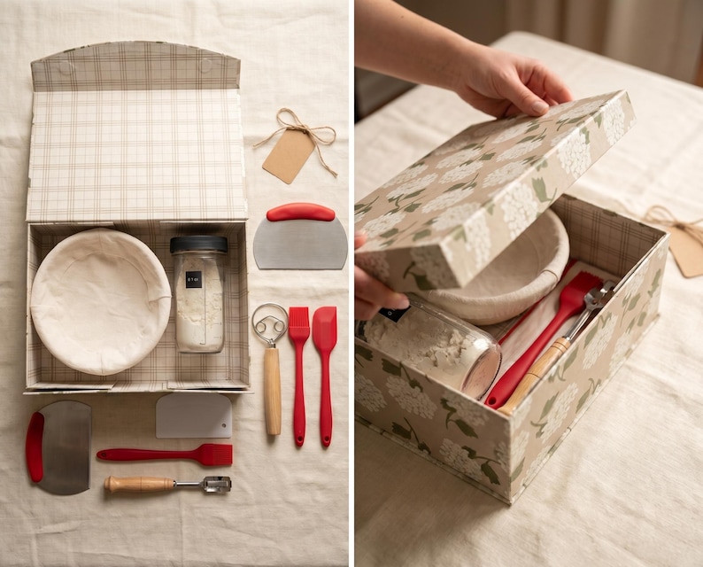 May include: A baking kit presented in a decorative box. The kit includes a proofing basket, a jar of flour, a dough scraper, a whisk, and two red silicone spatulas. The box has a plaid pattern on the inside and a floral design on the outside.
