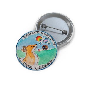 May include: A round button with a watercolor illustration of a fox looking up at rainbow-colored bubbles. The text "Respect Existence or Expect Resistance" is printed around the edge of the image. A second, unadorned button is visible in the background.