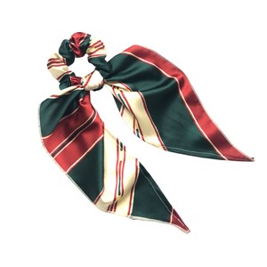 May include: A green, red, and cream striped hair scrunchie with long tails.