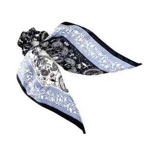 May include: Black and white paisley patterned hair scrunchie with a blue trim.