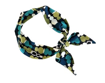 May include: A blue, green, and white patterned silk scarf tied in a bow. The scarf has a geometric pattern of abstract shapes.