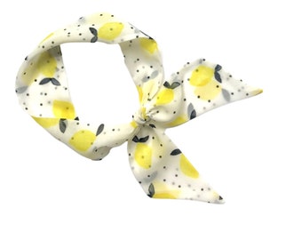May include: A white headband with a lemon print and black polka dots. The headband is tied in a bow.