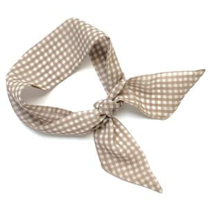 May include: A brown and white gingham hair scarf tied in a bow.