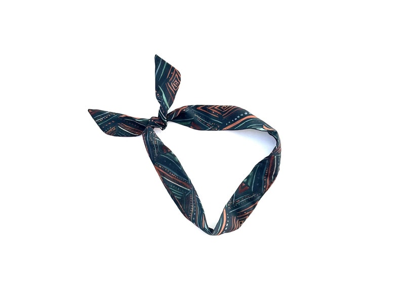 May include: A dark green and brown patterned fabric headband tied in a knot.